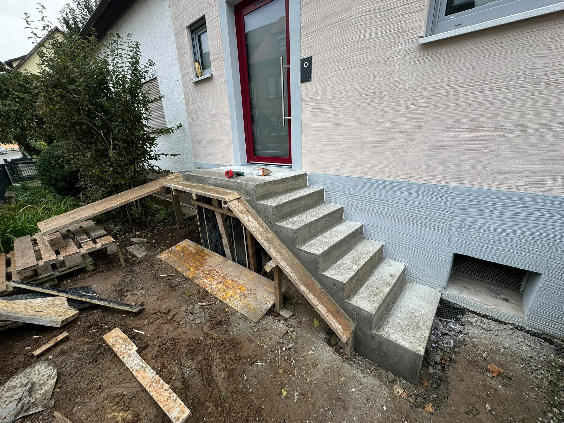 Betontreppe am Hauseingang mit seitlicher Holzschalung