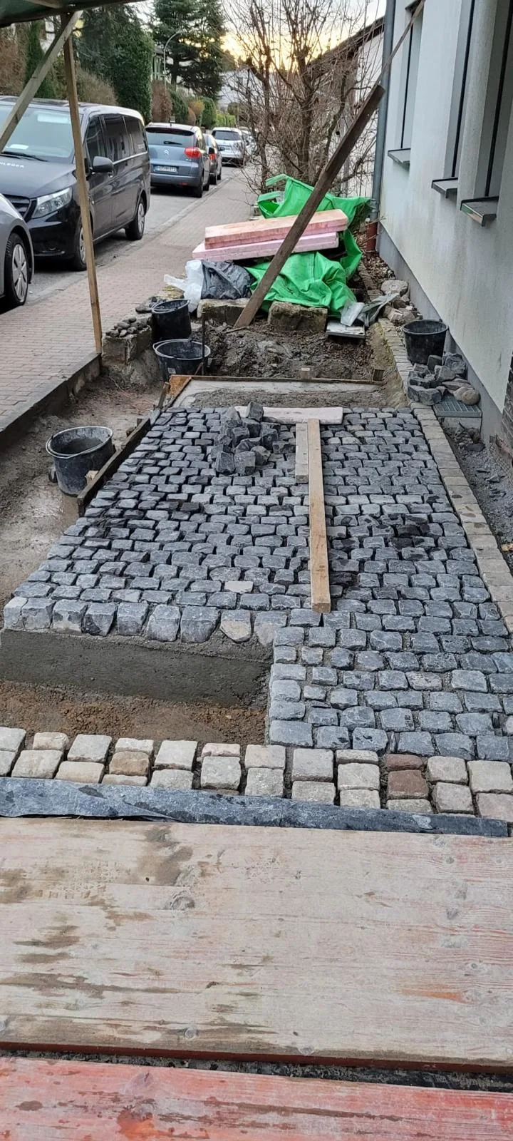 Eingefasste Pflasterfläche zwischen Hauseingang und Straße